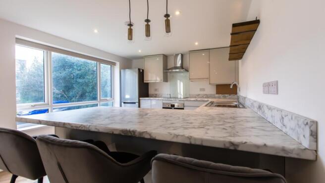 Bright modern kitchen with a large marble-effec...