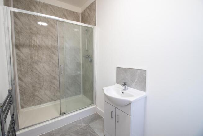 A clean, modern bathroom featuring a shower enc...