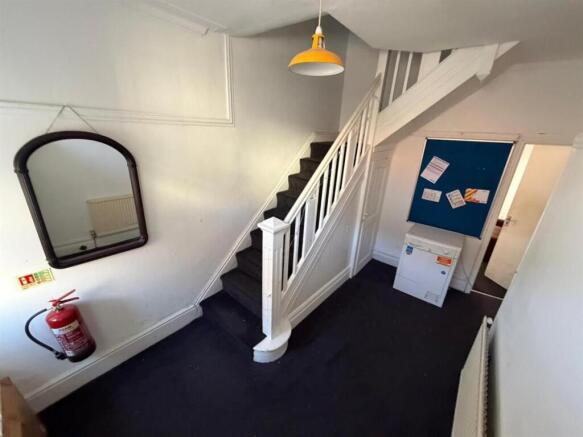 Bright, functional entryway with white staircas...