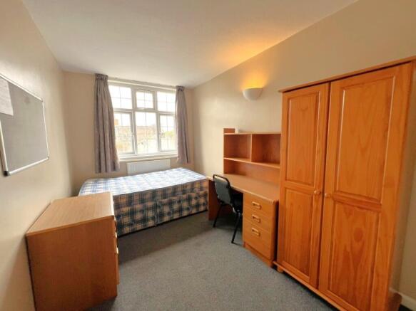 A cozy student bedroom featuring a single bed, ...