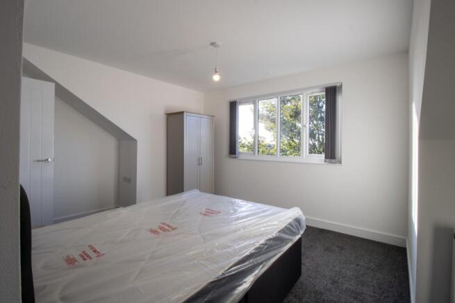 A bright and tidy bedroom with a large window l...