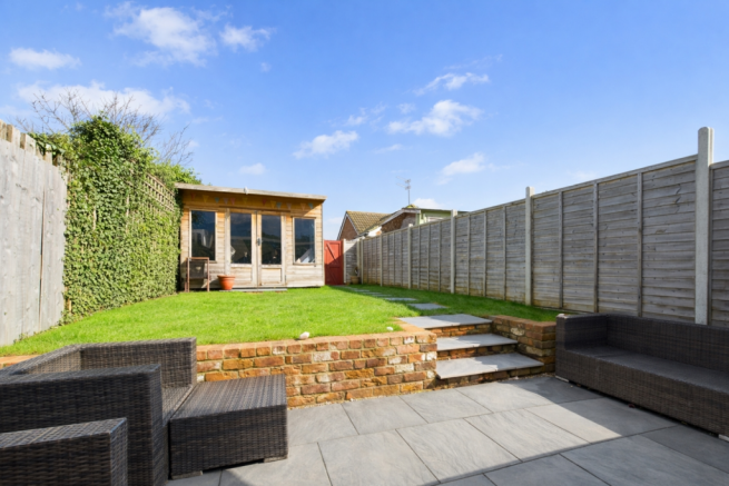 Sunny garden with rattan furniture and shed