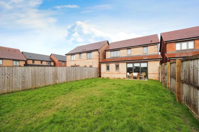 Large lawn and patio with bifolds to indoors