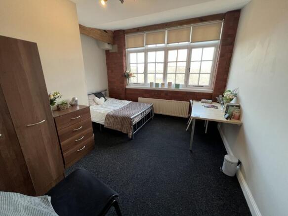 A well-lit, cozy single bedroom with a large wi...