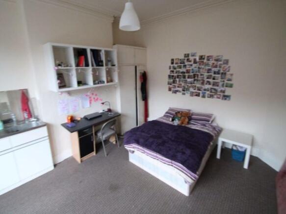 A cozy and tidy single bedroom featuring a comf...