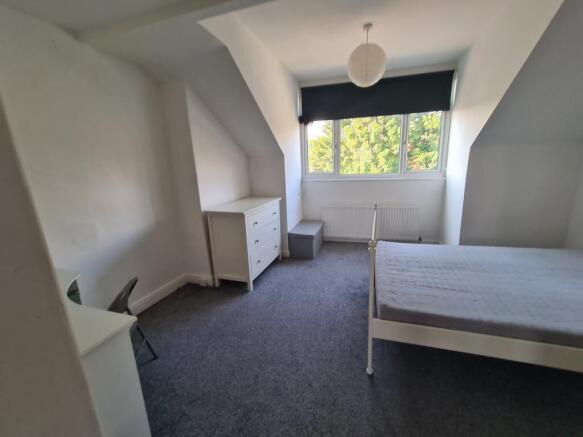 A bright and tidy bedroom featuring a large win...