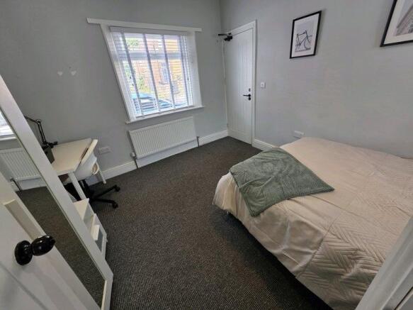 A neat and well-lit single bedroom featuring a ...
