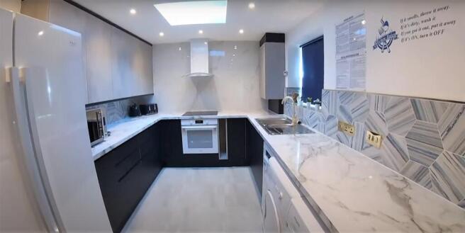 Modern fitted kitchen with marble-effect surfac...