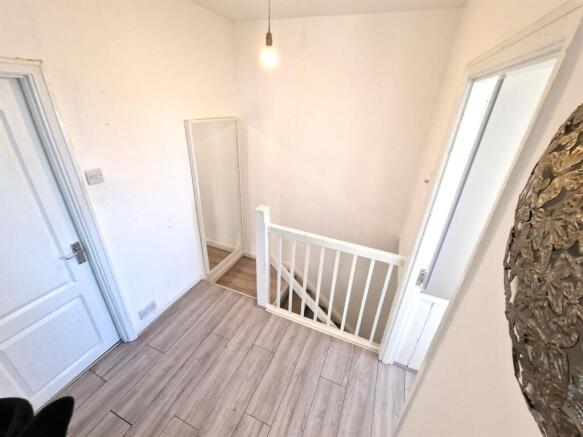 A clean and bright hallway with light wood floo...