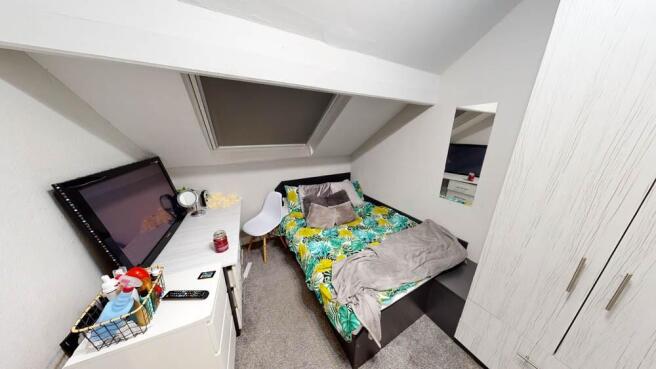 A cozy single bedroom featuring a neatly made b...
