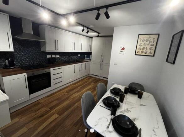 Modern fitted kitchen with long run of white ca...