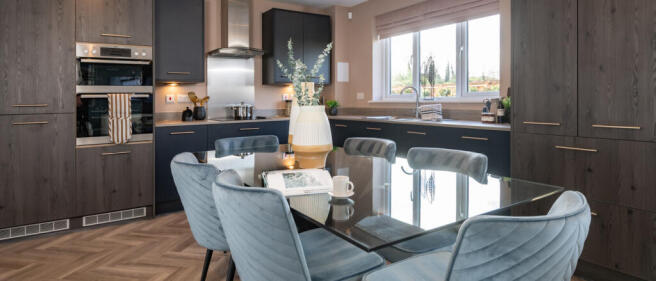 Modern kitchen with dark grey cabinets, a glass dining table, and light blue upholstered chairs, wit