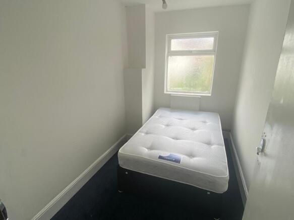 A compact single bedroom featuring a fresh, whi...