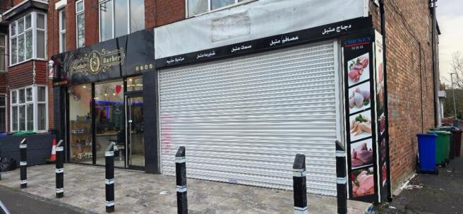Shopfront with roller shutter and adjacent barb...