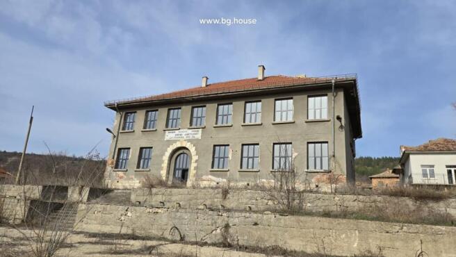Front view of the historic school building showing its symmetrical windows and arched entrance