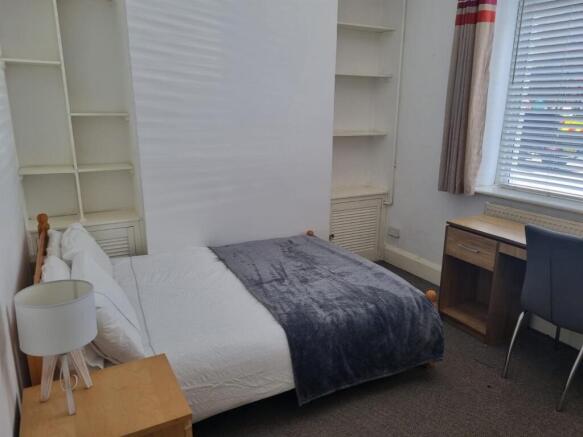 Bright bedroom with desk and built-in shelving...