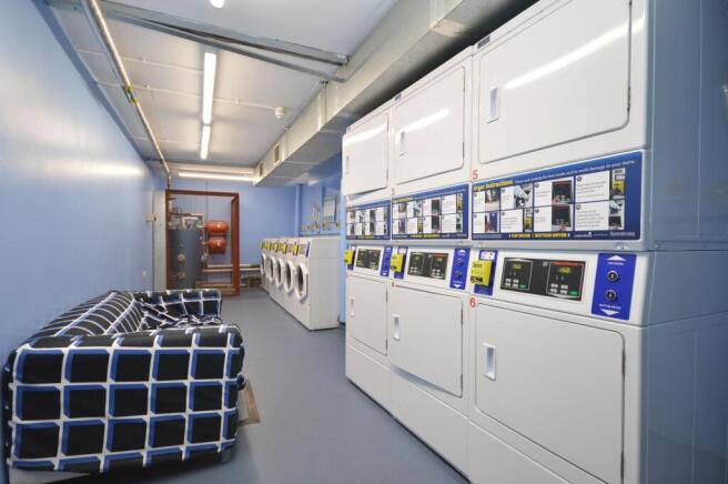 Bright, modern laundry with seating and stacked...