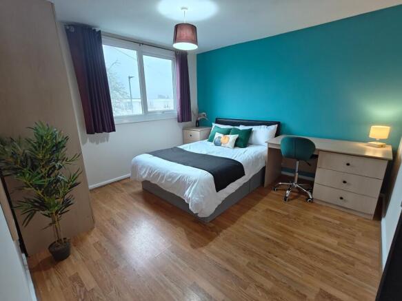 Bright bedroom with desk, storage and teal feat...