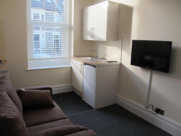 Compact studio lounge with kitchenette and TV...