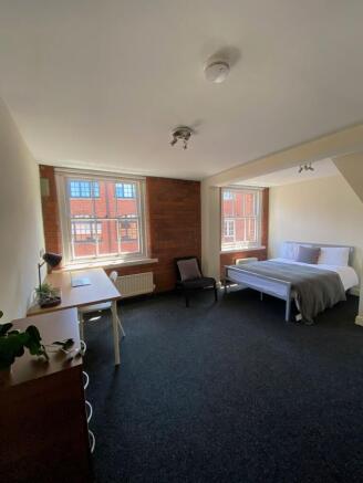 Spacious, bright bedroom with exposed brick det...