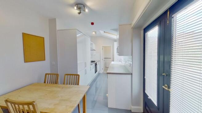 Bright, modern galley kitchen with white cabine...