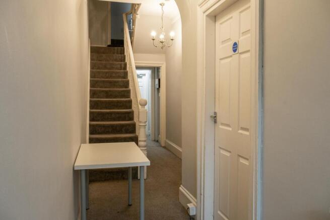 Bright, neutral hallway with carpeted stairs, w...