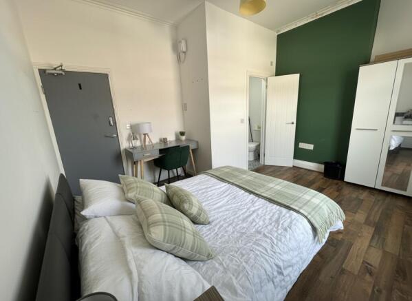 Bright bedroom with stylish desk and wood floor...