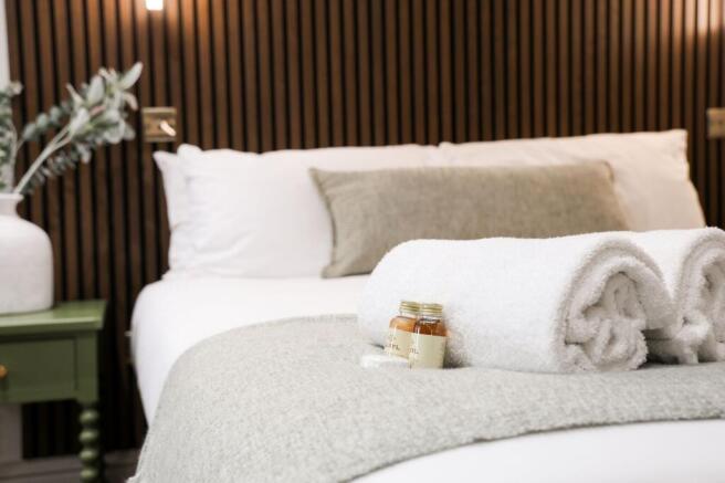 Freshly made double bed with towels and toiletr...