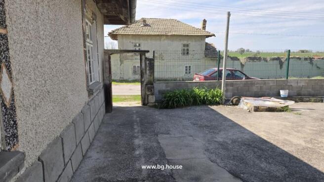 Concrete courtyard with garden plants near the open gate leading to the street