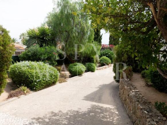 Private paved driveway and beautifully landscaped garden of a luxury villa for sale in Carvoeiro, Algarve. Peaceful residential setting near the beach.