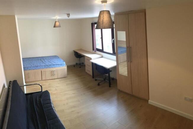 Spacious bedroom with ample desk and storage sp...