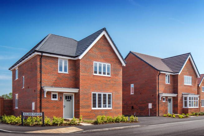 Two modern brick houses with white-framed windows stand on a paved street in front of a clear blue s