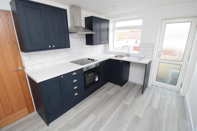 Modern kitchen with sleek navy units and natura...