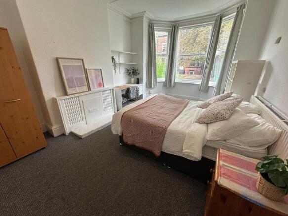 A bright and welcoming bedroom with a large bay...