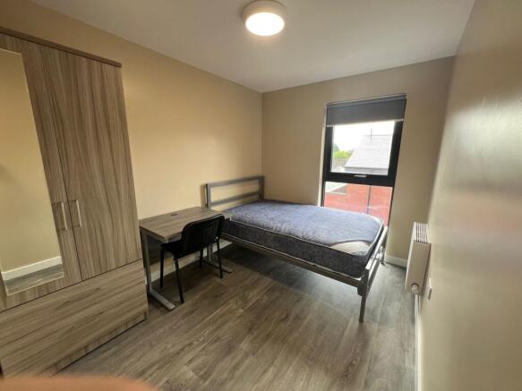 A well-lit, clean single bedroom featuring a be...