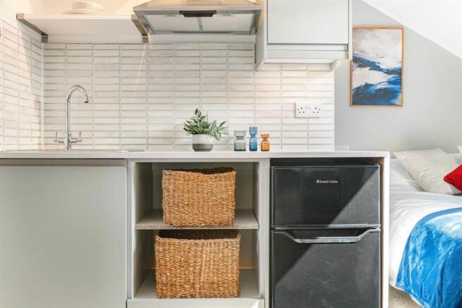 Modern studio kitchen with sleek white tiling...