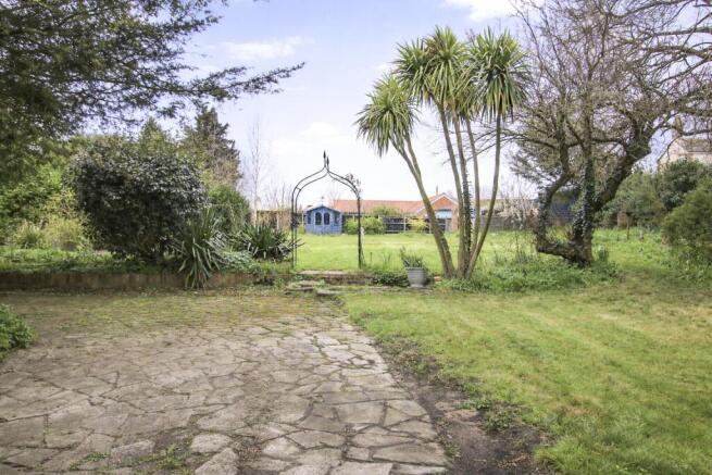 Lush garden with blue shed and archway.jpg
