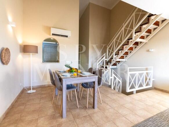 Modern dining area and stylish staircase in a triplex apartment at Gramacho Golf Resort, Algarve. Features a dining table set for six guests.