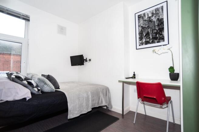 Bright, neatly staged bedroom with a comfortabl...