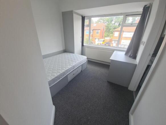 A neat and tidy single bedroom featuring a sing...