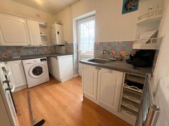 Compact fitted kitchen with white cabinetry, in...