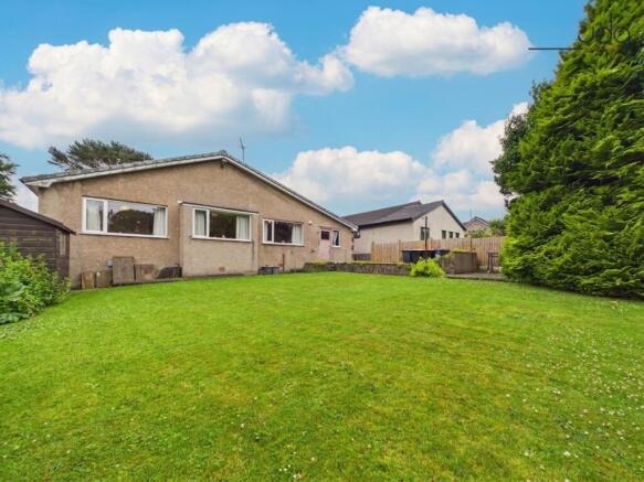 A generous lawned garden with mature planted borders and patio seating areas