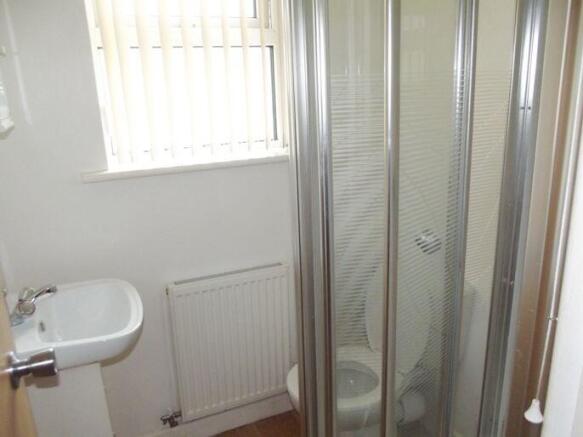 Compact, clean bathroom with a corner shower cu...