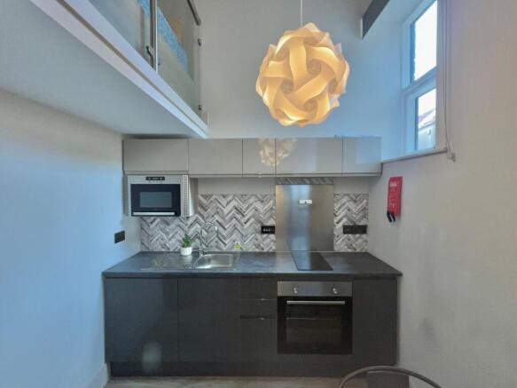 Modern compact kitchen with sleek dark lower ca...