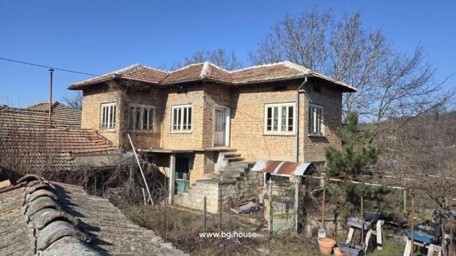 Exterior view of a two-storey brick house with tiled roof and stone staircase leading to the upper floor