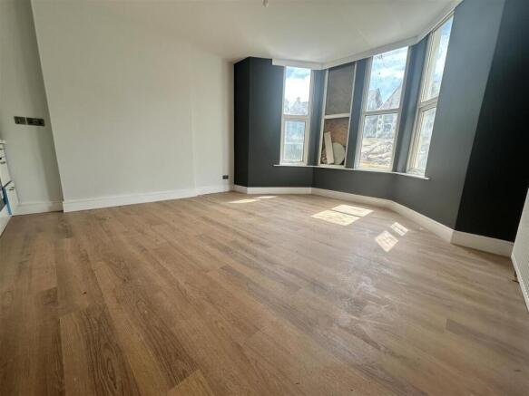 Bright lounge with a bay window and wood floors...
