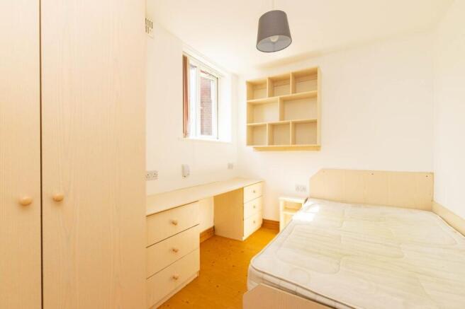 A bright, minimalist single bedroom furnished w...