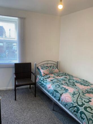 Bright bedroom with large window and comfy chai...