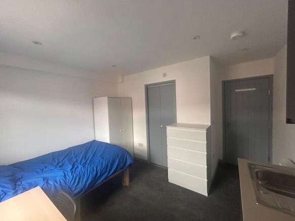 Compact room with bed, storage and kitchenette...