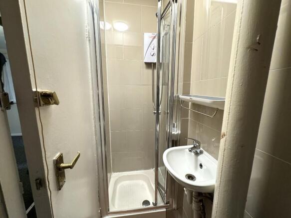 Compact tiled bathroom with a corner shower enc...
